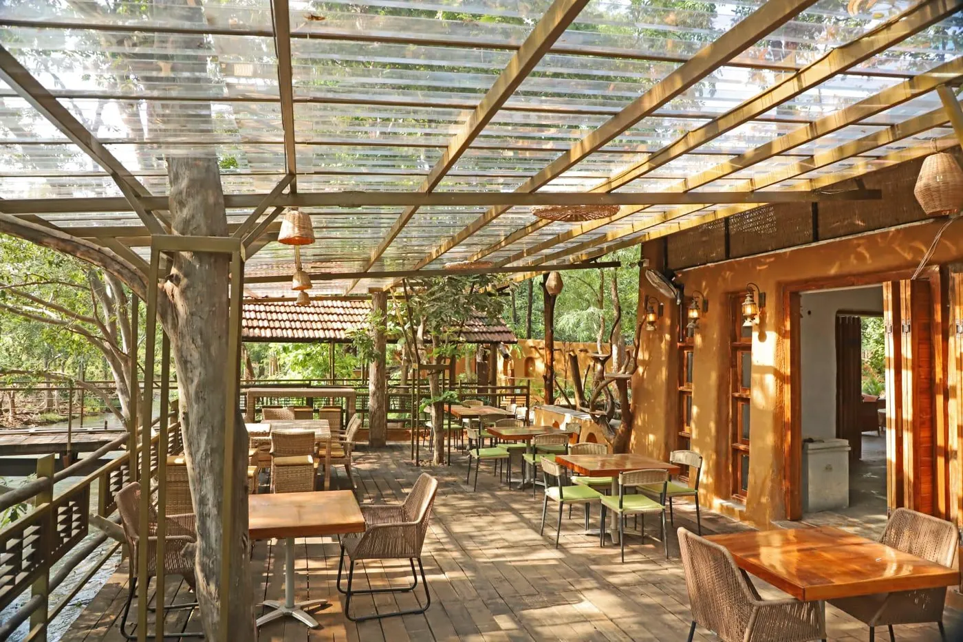 Riverdeck Mahua Restaurant with wooden tables under a glass and timber canopy
